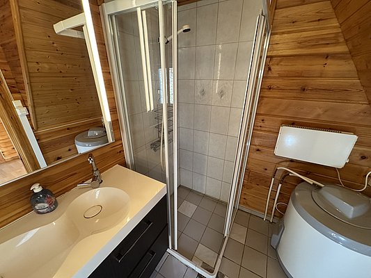 Modernes Bad in gemütlicher Hütte auf Hitra, Norwegen. Holzverkleidung, geräumige Dusche, Waschbecken mit Spiegel. Ideal für Angelurlauber, die Komfort und Naturverbundenheit suchen. Perfekter Rückzugsort nach einem erfolgreichen Angeltag.