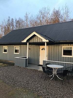 Gemütliches graues Ferienhaus in Hitra, Norwegen, mit überdachter Terrasse und Gartenmöbeln. Ideal für Angelreisen und Entspannung in atemberaubender Natur. Perfekter Ausgangspunkt für Meeresangeln und Abenteuer in der Umgebung.