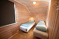 Gemütliches Schlafzimmer in einer norwegischen Hütte mit Holzverkleidung, zwei Einzelbetten und sanfter Beleuchtung. Ideal für erholsame Nächte während eines Angelabenteuers in Nordlands atemberaubender Natur.