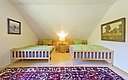 Gemütliches Schlafzimmer in Nordland, Norwegen: Zwei Betten mit grüner Bettwäsche, warmes Licht, bunte Teppiche. Perfekt für erholsamen Urlaub nach einem erfolgreichen Angeltag in der malerischen norwegischen Natur.