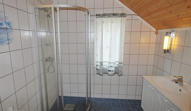 Helles, modernes Badezimmer in Norwegen, Region Hitra, mit Dusche, Waschbecken und weiß gefliesten Wänden. Ideal für Angeltouristen, die Komfort nach einem erlebnisreichen Tag suchen. Perfekte Unterkunft für Angelurlaub in bezaubernder Umgebung.