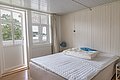 Ein gemütliches Schlafzimmer in der Region Hitra, Norwegen, mit heller Holzwand und großem Bett, bietet Blick auf die malerische Natur. Ideal für Angelurlaub und Entspannung in naturnaher Umgebung.