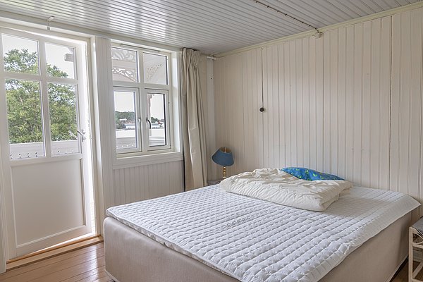 Ein gemütliches Schlafzimmer in der Region Hitra, Norwegen, mit heller Holzwand und großem Bett, bietet Blick auf die malerische Natur. Ideal für Angelurlaub und Entspannung in naturnaher Umgebung.