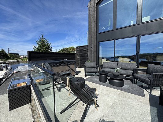 Moderne Terrasse in Südwest-Norwegen mit stilvollen Gartenmöbeln und Blick auf die Küste. Idealer Ausgangspunkt für Angelreisen, umgeben von Natur und maritimer Atmosphäre. PeRfekte Kombination aus Entspannung und Abenteuerlust.