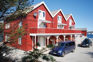 Rotes Ferienhaus am Wasser in Hitra, Norwegen, perfekter Ausgangspunkt für Angelurlaub. Klare blaue Himmel und Küstenlandschaft laden zu Abenteuern und Ruhe ein. Ideal für Meeresangeln und Entspannung.