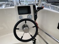 Das Bild zeigt das Cockpit eines Bootes mit einem Steuerrad, einem Monitor und mehreren Anzeigen.