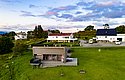 Kleines, modernes Ferienhaus in Norwegen, umgeben von üppigem Grün und traditionellen Gebäuden. Ideal für einen entspannten Angelurlaub in Nordland. Die Landschaft bietet Ruhe und atemberaubende Ausblicke, perfekt für Erholungssuchende.