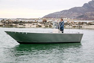 Ein Motorboot fährt entlang der malerischen Küste von Nordland, Norwegen. Ruhiges Wasser, felsige Ufer und beeindruckende Berge bieten eine perfekte Kulisse für Angelabenteuer und Naturerlebnisse.