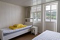 Helles Schlafzimmer in Hitra, Norwegen: schlicht eingerichtet mit zwei Betten, Holzvertäfelung und großen Fenstern mit Aussicht. Ideal für komfortable, naturnahe Übernachtungen auf Angelreisen.