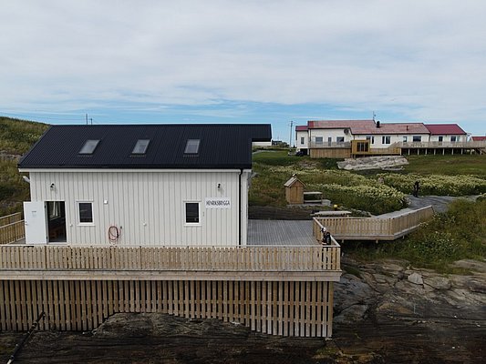 Gemütliches Ferienhaus in Nordland, Norwegen, mit moderner Holzveranda und malerischem Ausblick. Ideale Unterkunft für Angelreisen. Perfekte Mischung aus Natur und Komfort für unvergessliche Erlebnisse im skandinavischen Norden.