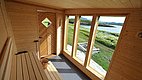 Sauna mit großen Fenstern in Nordland, Norwegen. Holzverkleidung, entspannter Ausblick auf Landschaft und Wasser. Perfekt für Angelurlaub und Erholung in skandinavischer Natur. Entdecke Meeresangeln und nordische Ruhe. Ideal für Outdoor-Abenteuer.