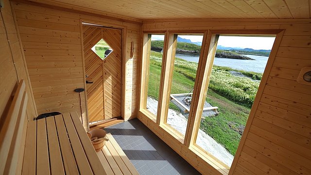 Sauna mit großen Fenstern in Nordland, Norwegen. Holzverkleidung, entspannter Ausblick auf Landschaft und Wasser. Perfekt für Angelurlaub und Erholung in skandinavischer Natur. Entdecke Meeresangeln und nordische Ruhe. Ideal für Outdoor-Abenteuer.