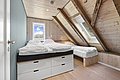Gemütliches Schlafzimmer in Südwest-Norwegen mit Holzwänden, zwei Einzelbetten unter Dachschrägen. Helles Tageslicht durch Fenster, beruhigende Atmosphäre. Ideal für erholsame Nächte nach einem erfolgreichen Angeltag in Norwegen.