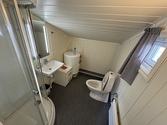 Kompaktes, helles Badezimmer in Hitra, Norwegen, mit Dusche, WC und Waschbecken. Ideal für Angelurlauber, die Komfort in der Unterkunft suchen. Perfekt nach einem erfolgreichen Tag am Wasser entspannen.