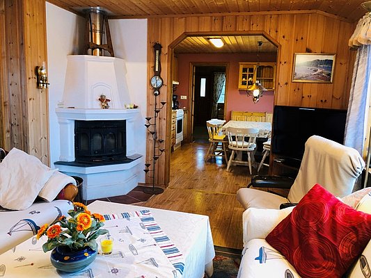 Gemütliches Ferienhaus in Hitra, Norwegen: Holzwände, Kamin und einladende Sitzecke. Ideal für Angelurlaub. Entspannung pur nach einem erfolgreichen Tag am Meer. Wohnlichkeit mit skandinavischem Flair. Perfekter Rückzugsort nach einem Angelabenteuer.