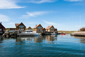 Küstenidylle in Südwest-Norwegen: Malerische Holzhäuser säumen das ruhige Hafenbecken, klare Himmel und spiegelndes Wasser laden zum Angelurlaub ein. Perfekter Ausgangspunkt für Meeresangeln und Erholung in skandinavischer Naturkulisse.