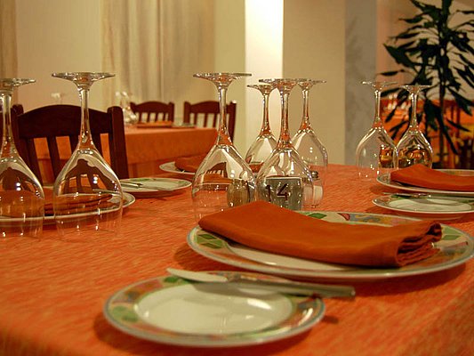 Ein stilvoll gedeckter Tisch mit umgedrehten Weingläsern, orangefarbenen Servietten und dekorativen Tellern, bereit für ein elegantes Dinner. Ein stilvoll gedeckter Tisch mit umgedrehten Weingläsern, orangefarbenen Servietten und dekorativen Tellern, bereit für ein elegantes Dinner.