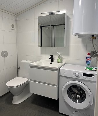 Modernes Badezimmer in Hitra, Norwegen, mit Waschmaschine, Spiegelschrank, Waschbecken und Toilette. Helle, funktionale Ausstattung für komfortable Aufenthalte während deines Angelurlaubs. Ideal für Erholung nach einem erfolgreichen Tag am Wasser.