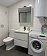 Modernes Badezimmer in Hitra, Norwegen, mit Waschmaschine, Spiegelschrank, Waschbecken und Toilette. Helle, funktionale Ausstattung für komfortable Aufenthalte während deines Angelurlaubs. Ideal für Erholung nach einem erfolgreichen Tag am Wasser.