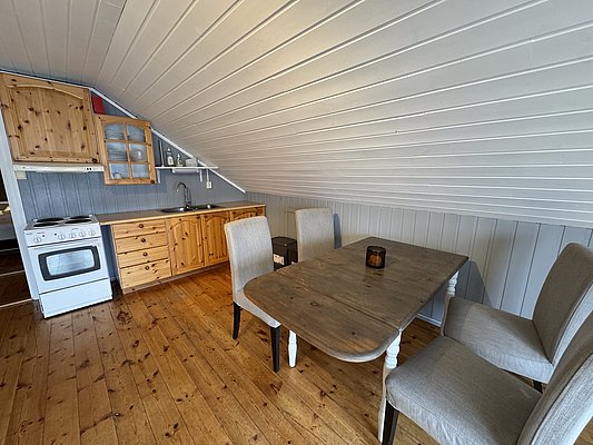 Gemütliche Ferienhaus-Küche in Hitra, Norwegen: Holzböden, rustikale Möbel, Komplettausstattung mit Herd und Spüle. Ideal für Angelreisen und entspannte Abende nach erfolgreichen Angeltagen. Perfekte Mischung aus Komfort und Abenteuer.