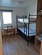 Helles, schlichtes Zimmer in Nordland, Norwegen, mit Etagenbett, Holzfußboden und Schreibtisch vor dem Fenster. Perfekt für Angelurlauber, die Komfort und Einfachheit schätzen. Ideal für erholsame Nächte nach spannenden Angelausflügen.