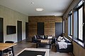 Gemütlicher Wohnbereich in Nordland, Norwegen, mit moderner Inneneinrichtung. Schwarze Ledersofas, Holzelemente und große Fenster schaffen eine warme Atmosphäre. Ideal für entspannte Angelreisen in der beeindruckenden Landschaft.
