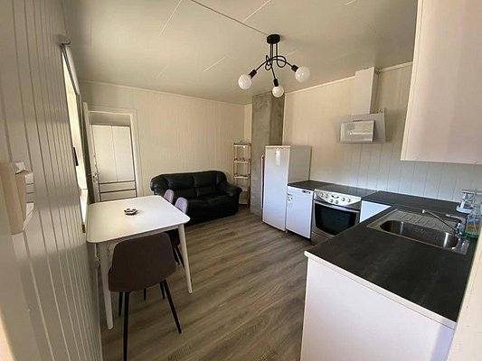 Gemütliche Ferienwohnung in Nord-Norwegen: Moderne Küche mit Herd, Kühlschrank und Spüle, angrenzender Essbereich, Sofa zur Entspannung. Perfekt für Angelurlauber, die Komfort und Abenteuer kombinieren möchten. Ideal für erholsame Aufenthalte nach erfolgreichen Angelausflügen.