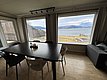 Modernes Wohnzimmer mit großem Esstisch, Panoramafenster bieten atemberaubenden Blick auf norwegische Fjordlandschaft in Hitra. Gemütliche Atmosphäre, perfekt für entspannten Angelurlaub oder Familienausflüge. Fantastische Naturkulisse lädt zum Entdecken ein.