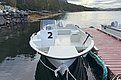 Ein weißes Angelboot liegt an einem Holzsteg in der malerischen Küstenregion Hitra, Norwegen. Ruhiges Wasser und bewaldete Hügel im Hintergrund schaffen eine entspannte Atmosphäre für einen Angelurlaub.