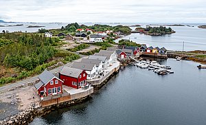 Die idyllische Küstenlandschaft von Hitra, Norwegen, zeigt traditionelle, bunte Fischerhütten am Wasser und eine ruhige, bewaldete Umgebung. Perfekt für Angelurlauber, die naturnahe Erholung und hervorragende Angelmöglichkeiten suchen.