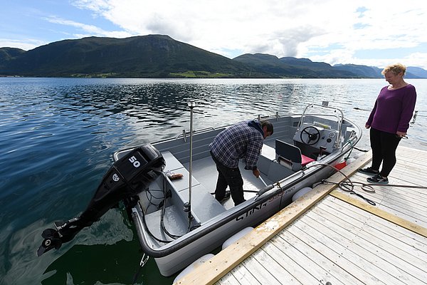 Ein kleines Motorboot liegt an einem Steg in der malerischen Küstenregion von Hitra, Norwegen. Perfekte Bedingungen für einen entspannten Angelurlaub in atemberaubender Naturkulisse.