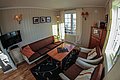 Gemütliches Wohnzimmer in Nord-Norwegen mit Holzmöbeln, bequemen Sesseln, Sofa, Flachbildfernseher und großen Fenstern. Ideal für entspannte Abende nach einem erlebnisreichen Angelurlaub. Helle, einladende Atmosphäre mit dekorativen Elementen.