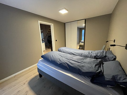 Ein modernes Schlafzimmer mit zwei Einzelbetten, blauer Bettwäsche und eingebautem Kleiderschrank. Einladendes Ambiente in Hitra, Norwegen, ideal für Angelurlaub und Entspannung.