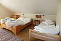 Gemütliches Schlafzimmer in Hitra, Norwegen: Drei hölzerne Einzelbetten mit weißer Bettwäsche und blauen Handtüchern, Holzboden, kleine Kommode. Ideal für entspannten Angelurlaub.