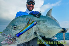 Glücklicher Angler hält riesigen Giant Trevally auf einem Boot vor der Küste Tanzanias. Klarer Himmel und weite See im Hintergrund. Ideal für Angelurlaub und unvergessliche Angelerlebnisse bei Andrees Angelreisen.