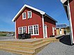 Rotes, skandinavisches Ferienhaus in Nordland, Norwegen, bei klarem blauen Himmel. Ideal für Angelreisen bietet die Unterkunft Komfort und Gemütlichkeit. Perfekte Basis für Abenteuer in beeindruckender Naturkulisse.