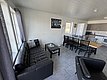 Gemütlicher Wohnbereich in Hitra, Norwegen: Moderne, helle Einrichtung mit schwarzem Ledersofa, großem Esstisch und offener Küche. Ideal für entspannte Angelurlaube. Perfekt für Gruppen oder Familien. Skandinavisches Design trifft Komfort.