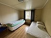 Gemütliches Zimmer in Hitra, Norwegen, mit zwei Einzelbetten, Holzboden und großem Fenster. Ideal für Angelurlauber, die Ruhe und Natur genießen möchten. Angenehme Beleuchtung, schlichtes Design für erholsame Nächte nach erfolgreichen Fischen.