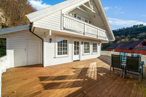 Gemütliches weißes Holzhaus in Süd-Norwegen mit sonniger Terrasse, umgeben von idyllischer Landschaft. Perfekt für einen entspannenden Angelurlaub mit herrlicher Aussicht und komfortabler Ausstattung. Ideal für Natur- und Angelfreunde.