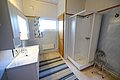 Helles Badezimmer in Nord-Norwegen mit Dusche, Doppelwaschbecken, gestreiftem Teppich und Fenster. Ideal für Angelreisende, die Komfort und Funktionalität nach einem erlebnisreichen Tag am Wasser suchen.