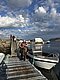 Angler hält großen Fisch auf Steg in Hitra, Norwegen, mit Boot im Hintergrund. Perfektes Ziel für Angelurlaub und Meeresangeln. Dramatischer Himmel und klare, ruhige See schaffen eine idyllische Atmosphäre für Abenteurer.