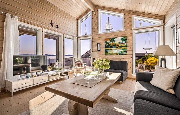 Gemütliches Wohnzimmer in Südwest-Norwegen mit Holzinterieur, großen Fenstern und Meerblick. Skandinavisches Design vereint Helligkeit und Naturverbundenheit. Ideal für Angelurlauber, die Komfort und beeindruckende Aussichten schätzen. Perfekte Kulisse für Entspannung und Abenteuerlust.