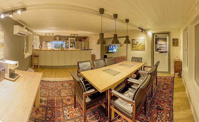 Gemütliche, moderne Küche und Essbereich in Nordland, Norwegen. Stilvolle Beleuchtung, Holzmöbel und bunte Teppiche schaffen eine einladende Atmosphäre. Perfekt für entspannte Abende nach einem erfolgreichen Angelurlaub.