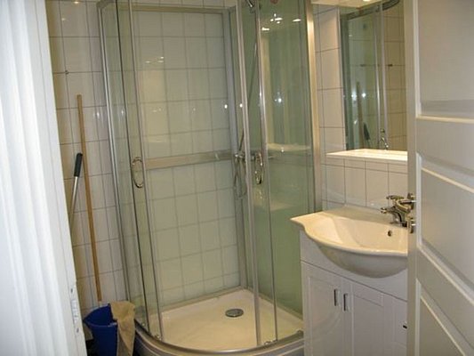 Modernes Badezimmer in Nordland, Norwegen mit Eckdusche, weiß gefliestem Design und praktischem Waschbecken. Funktionale Einrichtung für erholsamen Angelurlaub in den nordischen Regionen.