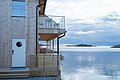 Modernes Holzhaus am ruhigen Fjord in Hitra, Norwegen. Glasbalkon mit Blick auf malerische Inseln. Ideal für Entspannung und Angelabenteuer in skandinavischer Natur. Perfekte Kulisse für Angelreisen und unvergessliche Erlebnisse.