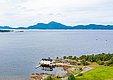 Luftaufnahme von Hitra, Norwegen: Küstenhaus am Wasser, umgeben von üppiger Natur und Bergen im Hintergrund. Ideal für Angelreisen und naturverbundenen Urlaub. Spektakuläre Landschaft zum Entspannen und Entdecken. Perfekter Rückzugsort für Abenteuer und Erholung.
