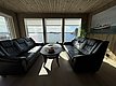 Gemütliches Wohnzimmer mit Panoramablick auf das Meer bei Hitra, Norwegen. Moderne Ledersofas, Holzwände und große Fenster schaffen eine einladende Atmosphäre zum Entspannen und Natur genießen. Perfekt für Angelurlaub und Erholung in skandinavischer Idylle.