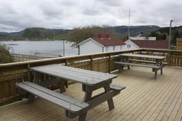 Große Holzterrasse mit Picknicktischen und Blick auf norwegische Fjordlandschaft in Hitra. Ideal für Angelurlaub mit Erholung in naturreicher Umgebung. Perfekt für gemütliche Pausen zwischen erfolgreichen Angelausflügen.