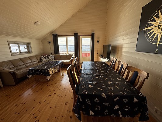 Gemütliches Ferienhaus in Hitra, Norwegen, mit Panoramablick auf das Meer. Rustikale Einrichtung, Esstisch für gesellige Stunden, perfekte Basis für Angelabenteuer. Ideal für erholsame Angelreisen an der norwegischen Küste.