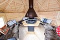 Gemütliche Grillhütte in Nord-Norwegen mit Holzverkleidung, zentralem Kamin, Sitzbänken mit Rentierfellen und Kissen. Perfekt für entspannte Angelurlaube und gemütliche Abende nach erfolgreichen Angelausflügen in der unberührten Natur. Petri Heil!